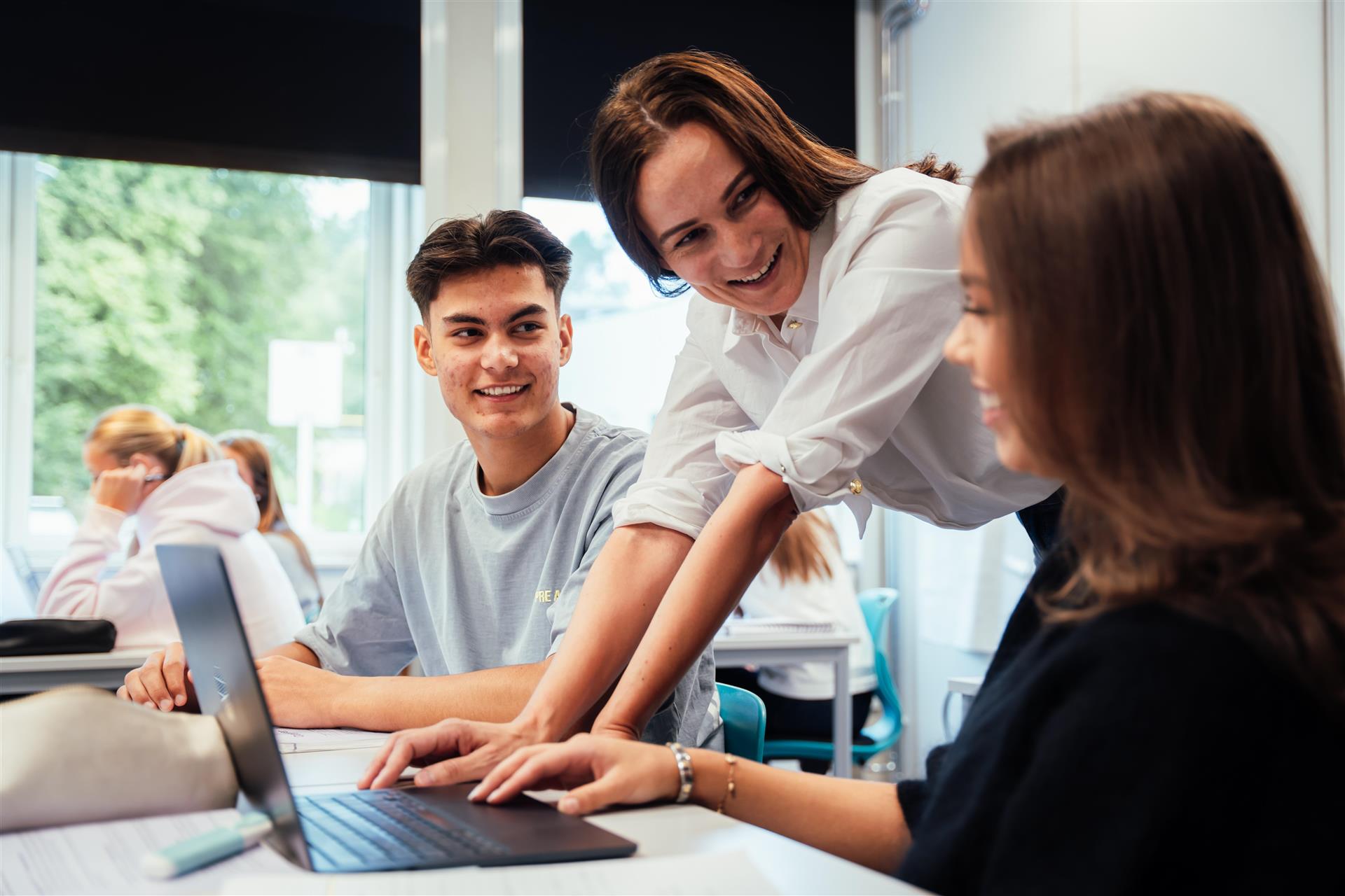 Bilde av elevar ved ein skrivepult